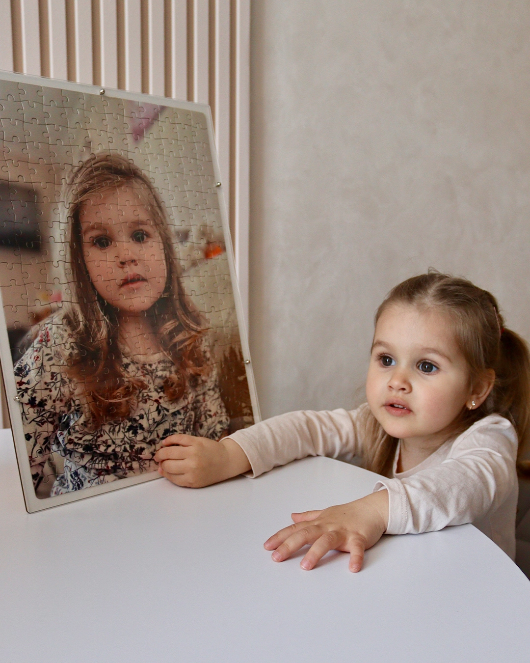 Дівчинка поруч із готовими фотопазлами зі своєю фотографією — подарунок для дітей